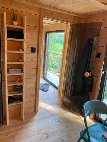 una stanza con una parete di legno con una grande finestra di Le Moonloft insolite Tiny-House dans les arbres & 1 séance de sauna pour 2 avec vue panoramique a Osenbach