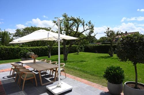 einen Tisch und Stühle mit Sonnenschirm im Hof in der Unterkunft House C in De Haan