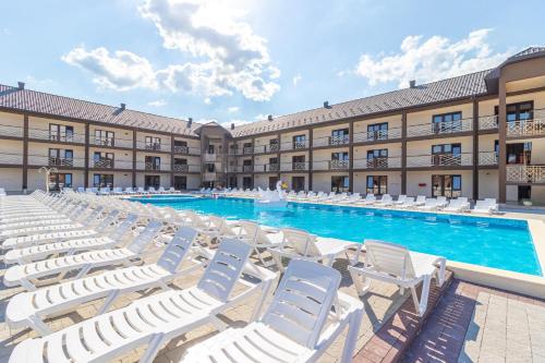 a large pool with white lounge chairs in front of a building at Nikoletta in Solotvyno