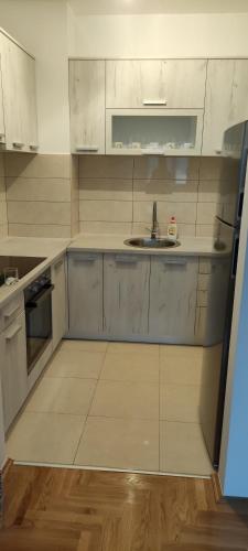 Una cocina con gabinetes blancos y un fregadero. en Apartman Mateja, en Trebinje