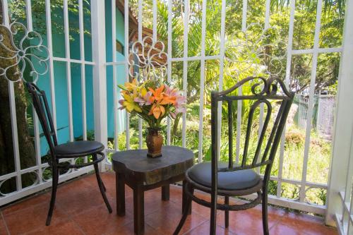a vase of flowers sitting on a table with two chairs at Oceanfront Hotel Verde Mar direct access to the beach in Manuel Antonio