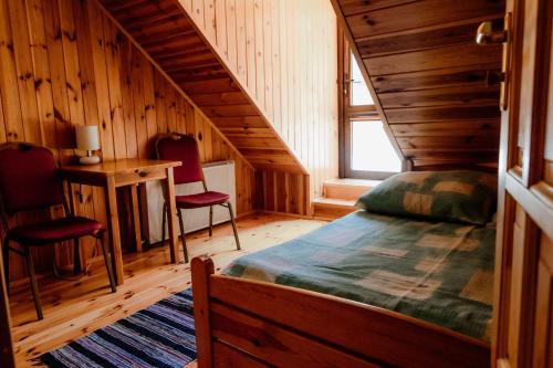 a bedroom with a bed and two chairs in a cabin at Gosciniec Uzmauda in Wiżajny
