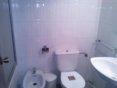 a white bathroom with a toilet and a sink at Pension Rioja in Quinto