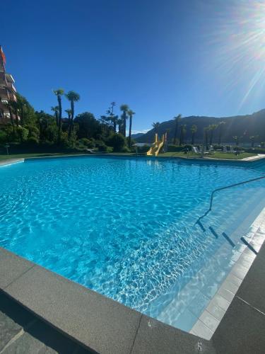 a large blue swimming pool with a slide in the background at Holiday on the Lake Lugano in Bissone