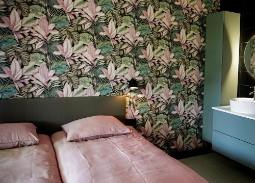 1 dormitorio con cama y papel pintado con motivos florales en Vakantiehuisje De Barones, en Middelburg