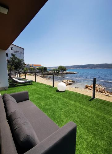 a couch sitting on the grass next to a beach at Beach apartment Paklenica-Deluxe in Seline