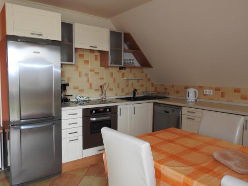 a kitchen with a table and a stainless steel refrigerator at Petra Apartmanház in Badacsonytomaj