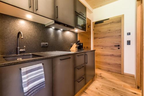 cocina con fregadero y puerta de madera en alpdeluxe-Apartments Holzgau, en Holzgau