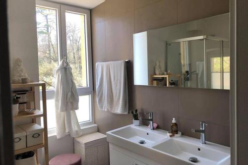 baño con lavabo, espejo y ventana en Vöens, St-Blaise, Logement entier - 2 chambres, en Marin