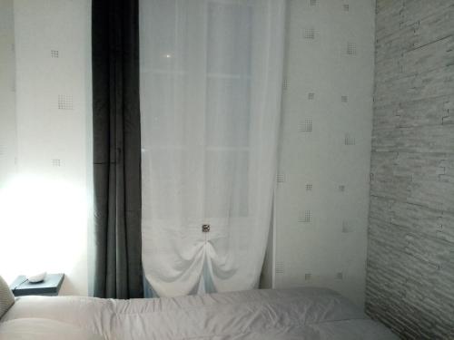 - une chambre avec un lit et un rideau blanc dans l'établissement Le petit Saint Bernard, à Dijon