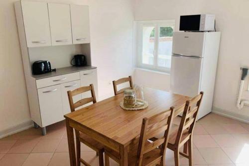 eine Küche mit einem Holztisch mit Stühlen und einem Kühlschrank in der Unterkunft Charmant appartement T2 hypercentre de Mazamet in Mazamet