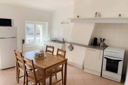 - une cuisine blanche avec une table en bois, une table et des chaises dans l'établissement Charmant appartement T2 hypercentre de Mazamet, à Mazamet