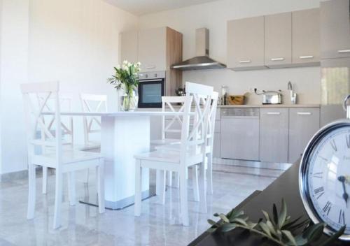 a kitchen with white chairs and a table with a clock at Island Residence in Sali