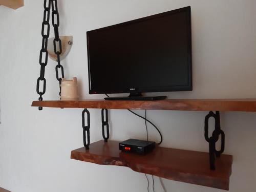 TV colgada en una pared con una estantería de madera en Our House Apartments en Kolašin