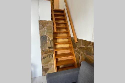 a staircase in a room with a couch and a stone wall at PANOS ROOMS Central loft studio near the beach in Andros
