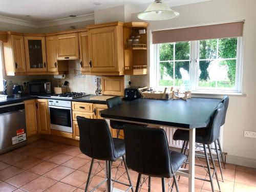 eine Küche mit Holzschränken, einem schwarzen Tisch und Stühlen in der Unterkunft Lakeside Cottage in Killaloe