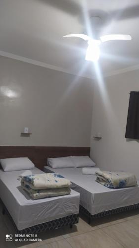two beds in a room with a ceiling fan at Pousada Quarto com ar, wi fi,frigobar perto da basilica in Aparecida