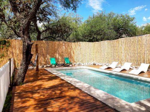 a swimming pool with chairs and a fence at Entre Sierras y Pajaros in Las Rabonas