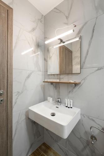 a white bathroom with a sink and a mirror at Regos Resort Hotel in Neos Marmaras