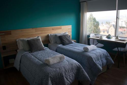 1 dormitorio con 2 camas, mesa y ventana a DREAM SUITES BRC en San Carlos de Bariloche