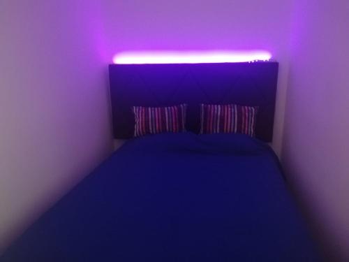 łóżko w pokoju fioletowym z oświetleniem w obiekcie Flamingo Apartment w mieście Portimão