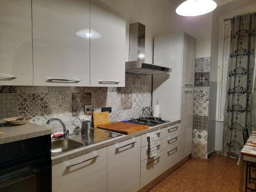 ジェノヴァにあるAppartamento Tolemaideの白いキャビネットとシンク付きのキッチン