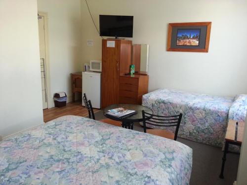 a room with two beds and a table and a tv at Sonbern Lodge Motel in Wallaroo