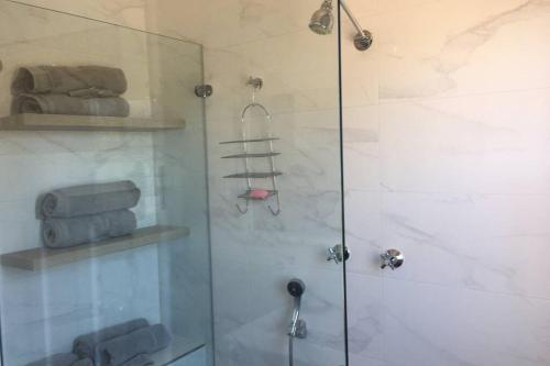 a shower with a glass door and some towels at The Hermitage in Cooma