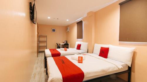 two beds in a room with red and white at RedDoorz at Hotel Rosemarie in Manila