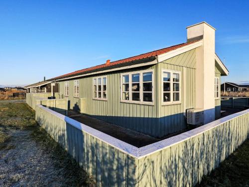 ein grünes Haus mit einem Zaun davor in der Unterkunft 6 person holiday home in L kken in Løkken