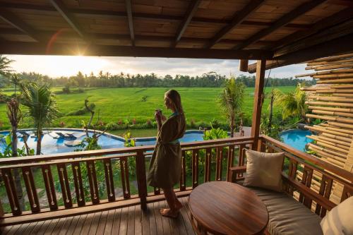 a woman standing on the balcony of a resort at Beehouse Dijiwa Ubud in Ubud