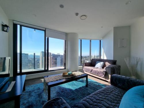 a living room with a couch and a table and large windows at Oceania City Fringe w Views Free Parking WiFi in Auckland