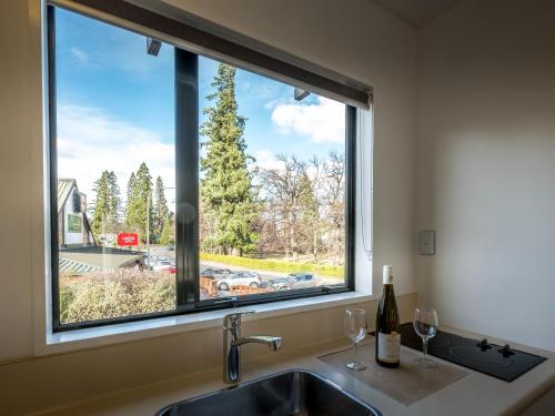 una finestra della cucina con lavandino e bicchieri da vino di ASURE Hanmer Inn Motel Hanmer Springs a Hanmer Springs