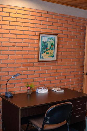 an orange brick wall with a desk and a chair at La Casa de Mamá Coyita in Cartago