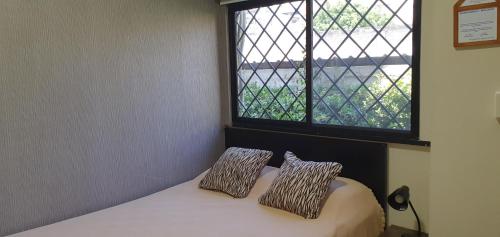 1 cama con 2 almohadas en una habitación con ventana en Apartamento habitación pequeña para ejecutivos o parejas, en Manta