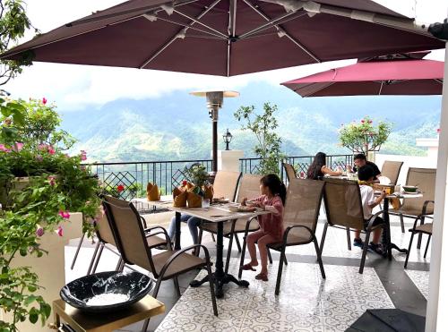 a group of people sitting at tables under an umbrella at Cat Cat Galerie d’Art in Sa Pa