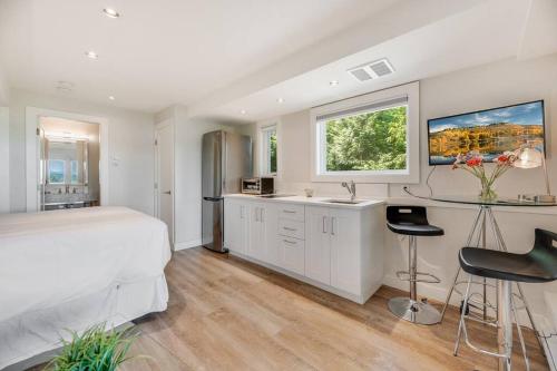 een witte slaapkamer met een bed, een bureau en stoelen bij Sea-esta Suite with Ocean Views in Brentwood Bay in Brentwood Bay