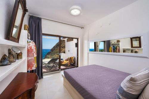 a bedroom with a bed and a view of the ocean at Moschatos Beach House in Kamari