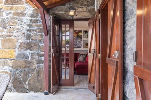 an open door into a stone house with a red couch at Recanto Jardim Do Mar in Jardim do Mar
