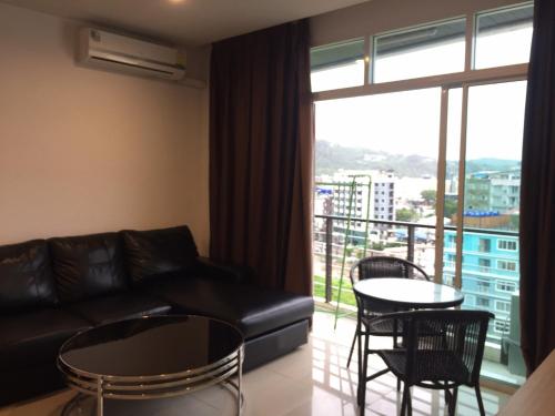 un soggiorno con un divano, tavoli e una finestra di The C Park a Patong Beach
