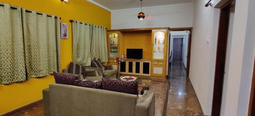 a living room with a couch and chairs and a tv at Garden House in Mysore