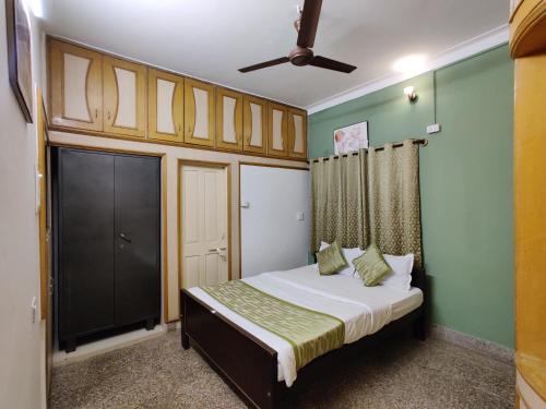 sypialnia z łóżkiem i wentylatorem sufitowym w obiekcie Garden House w mieście Mysuru