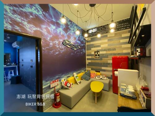um quarto com um sofá e um mural espacial em 澎湖 玩聚背包民宿 em Huxi