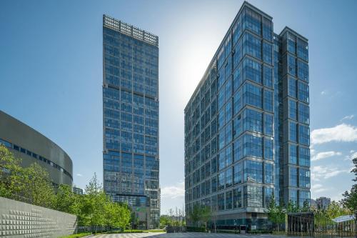 um edifício de vidro alto ao lado de dois edifícios altos em Holiday Inn Beijing Focus Square, an IHG Hotel em Pequim