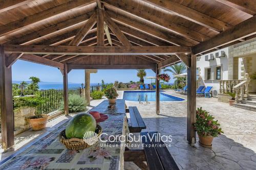 een houten pergola met een tafel en een zwembad bij PARADISE VILLA by Coral Sun Villas in Kato Yialia