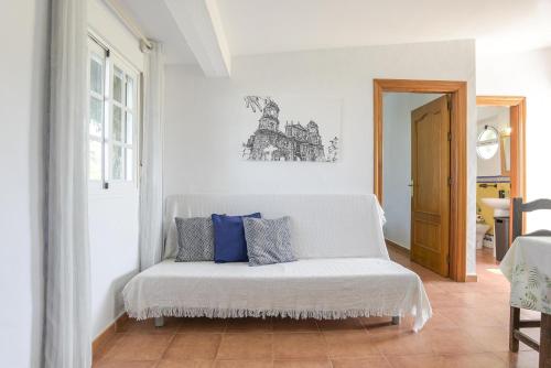 a white room with a couch with blue pillows on it at Finca Abril 2 Piscina Compartida in Roche