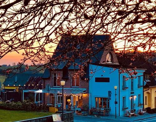 Ráj na zemi venkovský hotel a kavárna في Hukvaldy: مبنى أزرق مع غروب الشمس في الخلفية