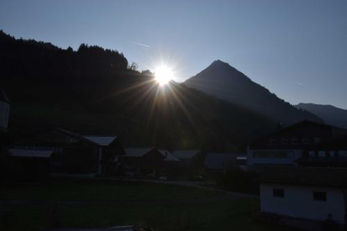 a sun setting over a mountain with a village at Haus Bianca in Schoppernau