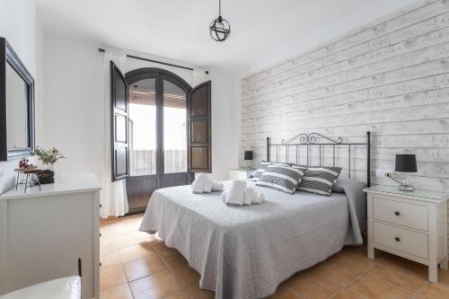 ein weißes Schlafzimmer mit einem Bett und einer Ziegelwand in der Unterkunft Duplex Las Terrazas in Vélez de Benaudalla