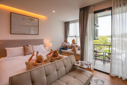 The Proud Rawai Resort في شاطئ راوايْ: ثلاث فتيات يجلسن على سرير في غرفة نوم